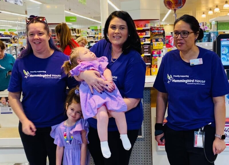 people dressed in purple including a woman holding a child who has a disability